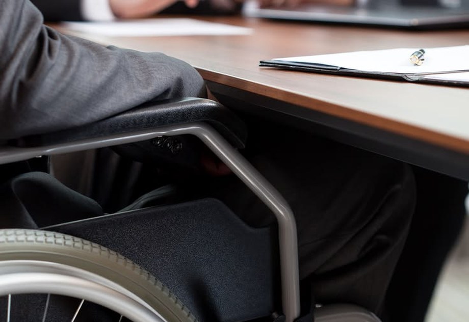 Borrower in a wheelchair meeting an advisor at a desk — Lending Buddy loans for benefits income