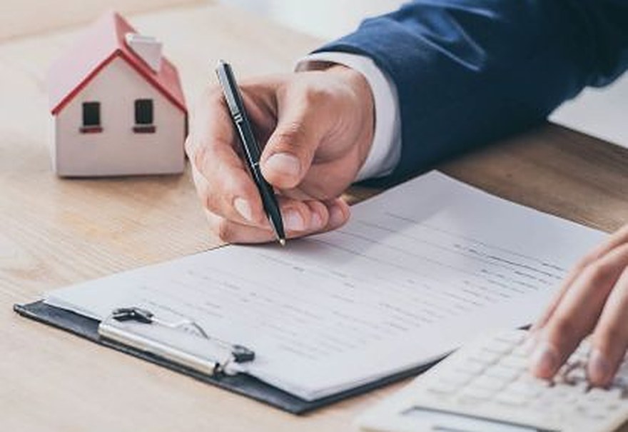 Homeowner reviewing refinance paperwork with a calculator — Lending Buddy mortgage refinance